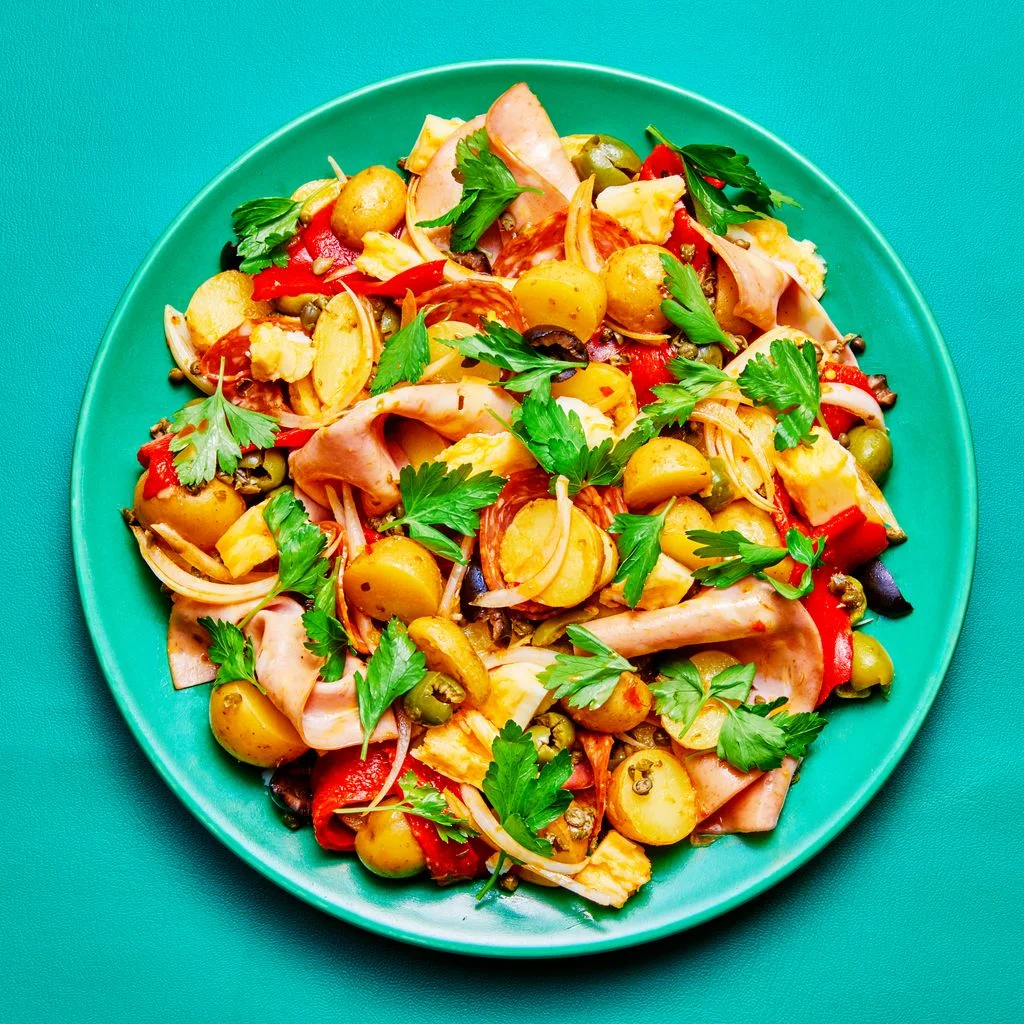A Muffuleta salad on a turqiose colored plate and background.
