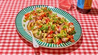 Colorful chaatstyle potato salad with fresh herbs tomatoes and crispy pita chips on a picnic table.