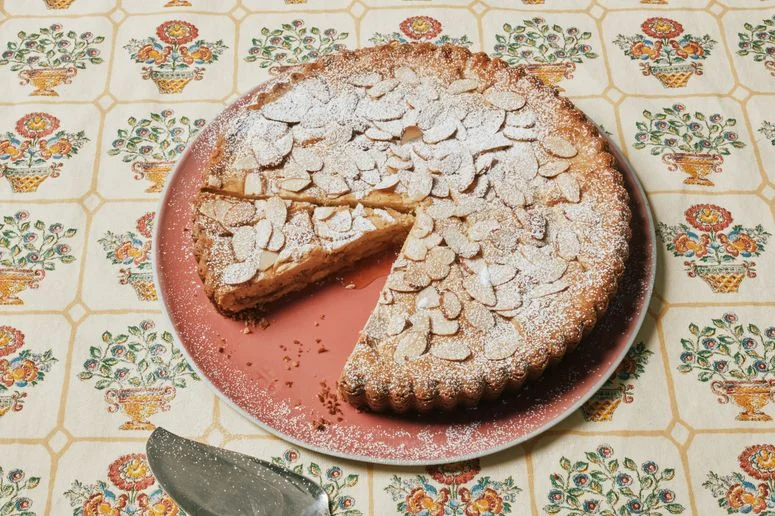 An almond apricot crostata sliced on a cake plate.