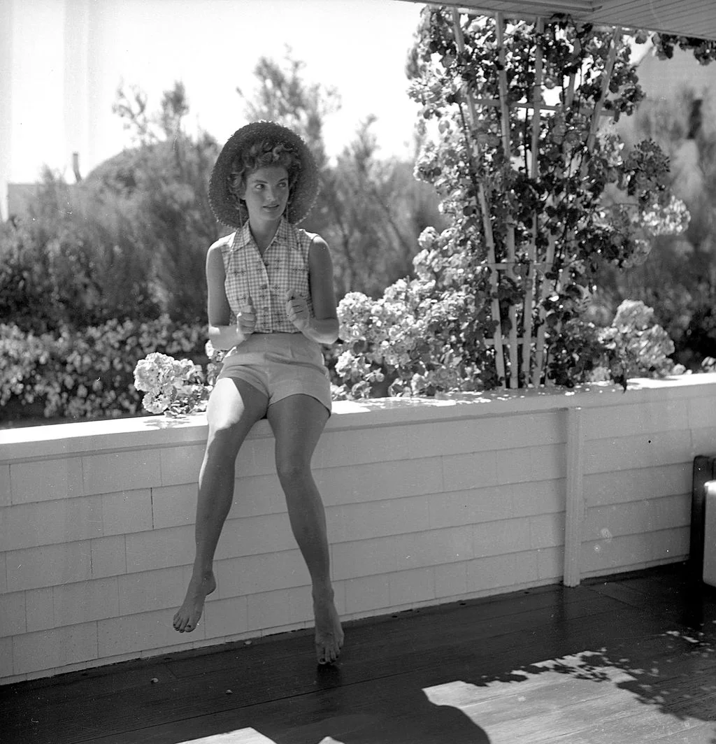 Image may contain Jacqueline Kennedy Onassis Clothing Shorts Hat Sun Hat Plant Potted Plant Child Person and Face