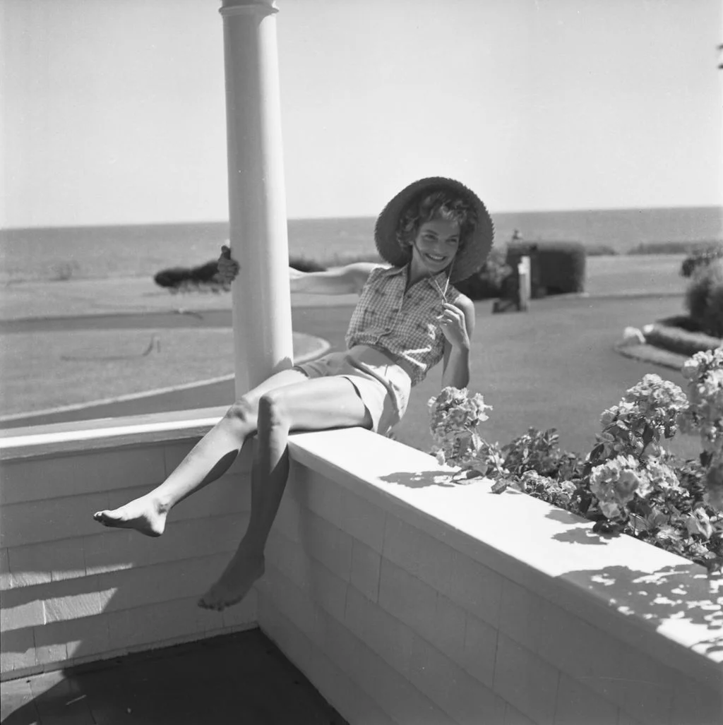 Image may contain Jacqueline Kennedy Onassis Clothing Hat Plant Potted Plant Sun Hat Adult Person Shorts and Face