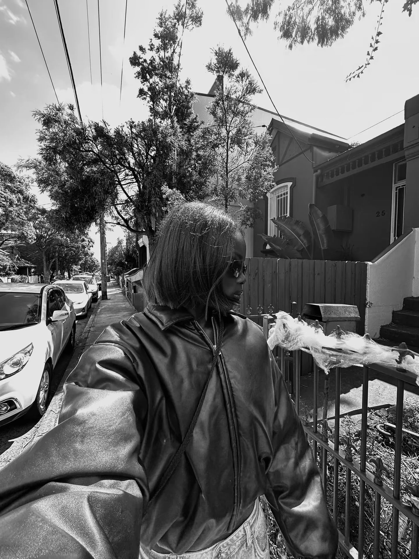Image may contain Clothing Coat Jacket Neighborhood Handrail Adult Person Plant Tree Car and Transportation