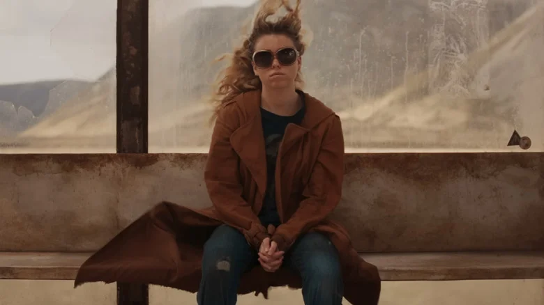 Milly Alcock as Kara Zor-El sitting at the bus stop in Supergirl