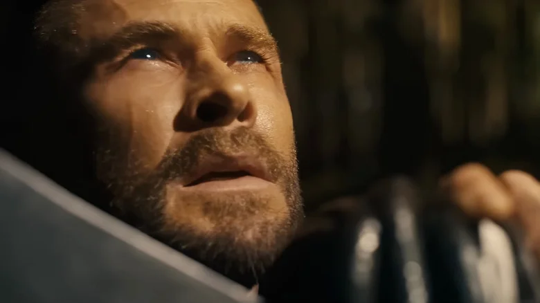Chris Hemsworth as Thor holding his battle axe in front of his face and looking upwards in Avengers: Doomsday
