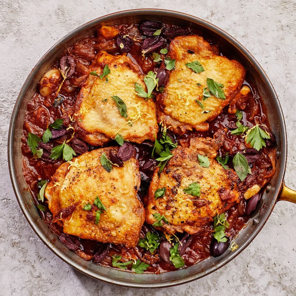 braised chicken thighs with olives and herbs in a large skillet