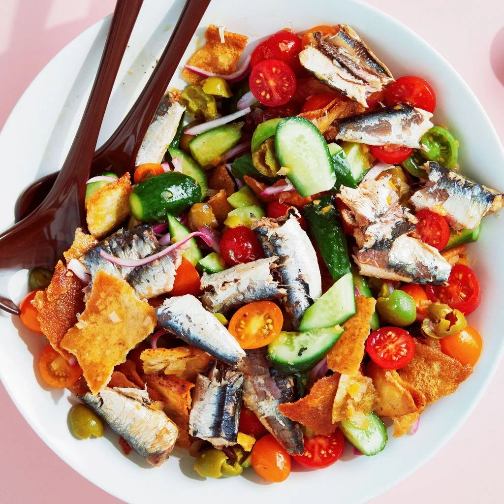Broken up oilpacked sardines in a bowl with chopped preserved lemons Persian cucumbers cherry tomatoes red onions mixed...