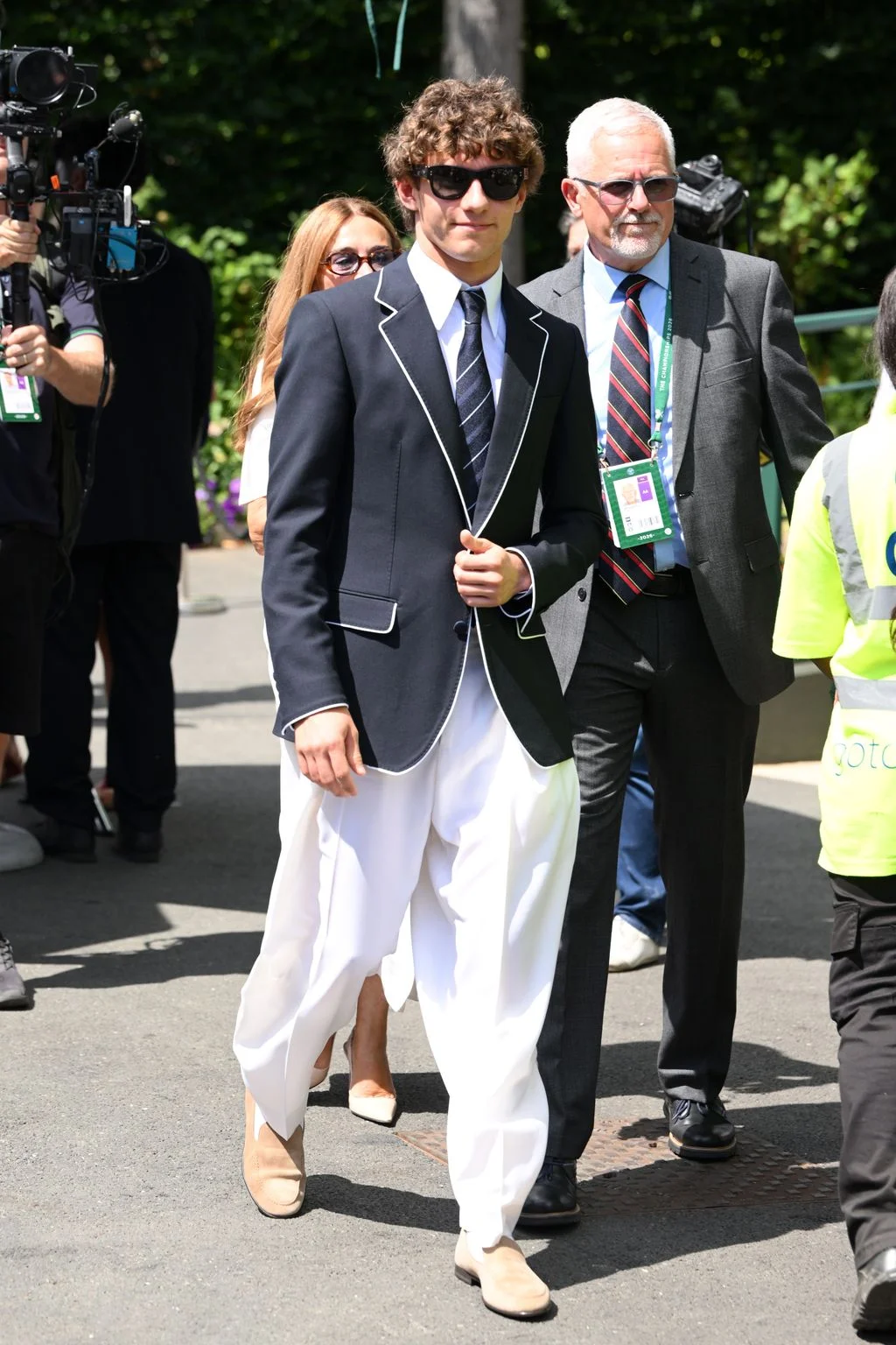 Image may contain Blazer Clothing Coat Jacket Formal Wear Suit People Person Accessories Sunglasses Tie and Adult