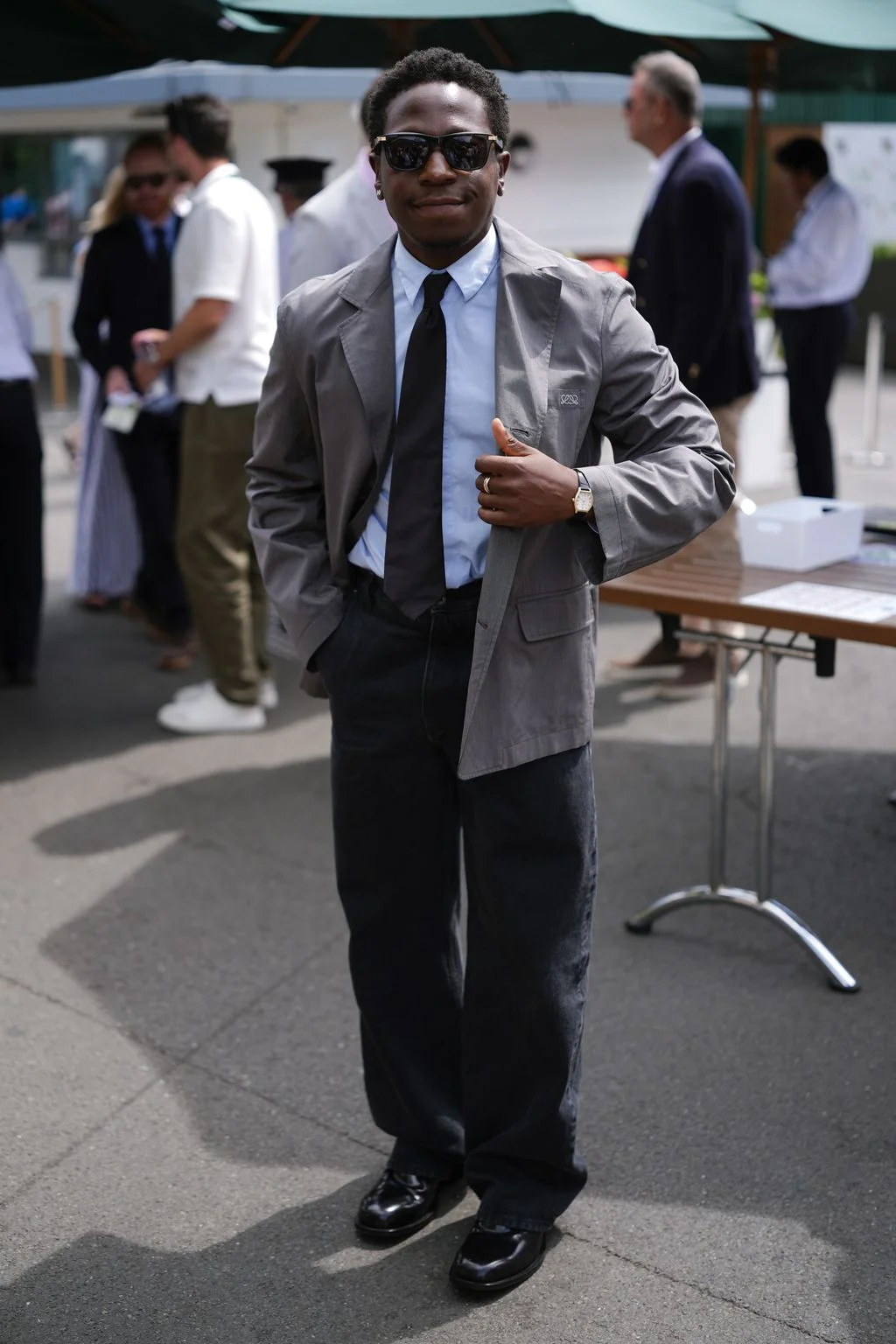 Image may contain Clothing Coat Formal Wear Suit Blazer Jacket Person Standing Accessories Tie Adult and Glasses