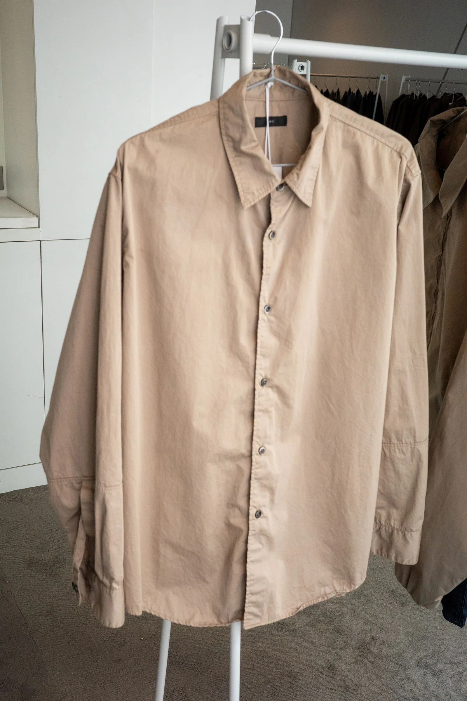 A beige buttonup on a hanger