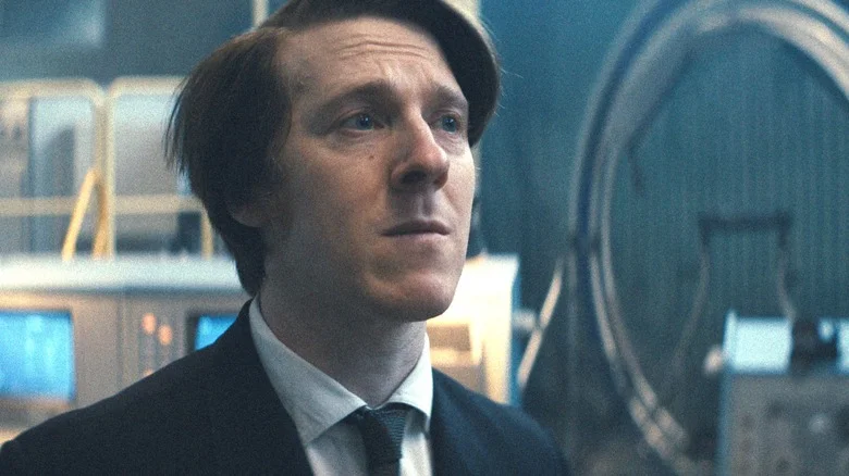 Adam Nagaitis as Valya Mironov standing in a suit with a worried look on his face in Star City
