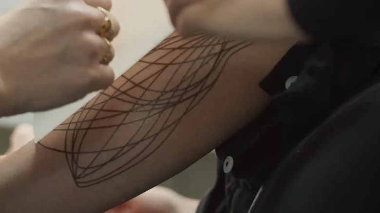A makeup artist working on Juliette's tattoos from Silo