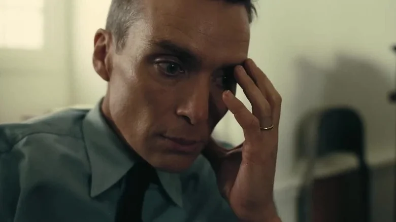 Cillian Murphy as J. Robert Oppenheimer holding his face in Oppenheimer