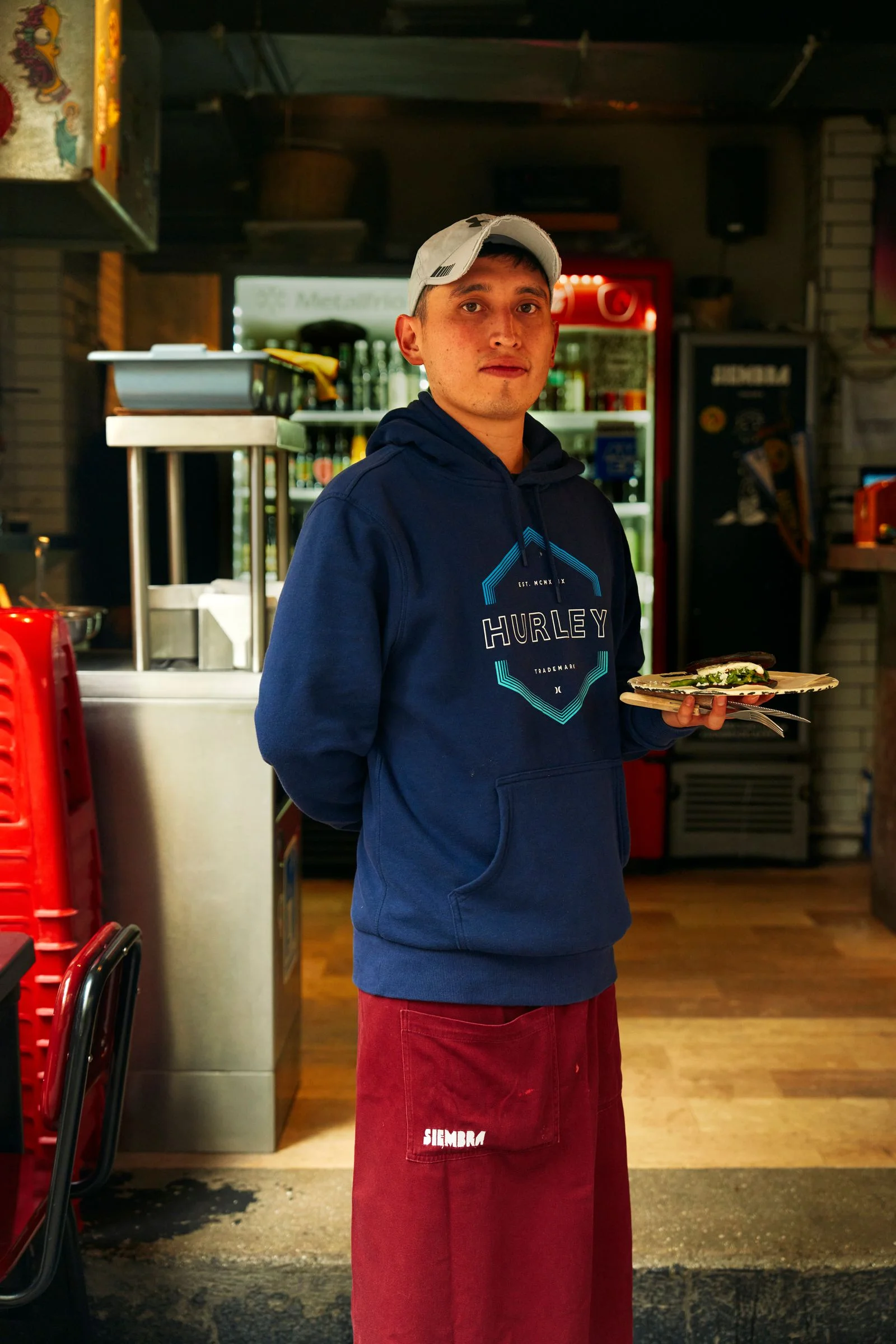 Image may contain Face Head Person Photography Portrait Clothing TShirt Adult Cap Hat Baseball Cap and Food