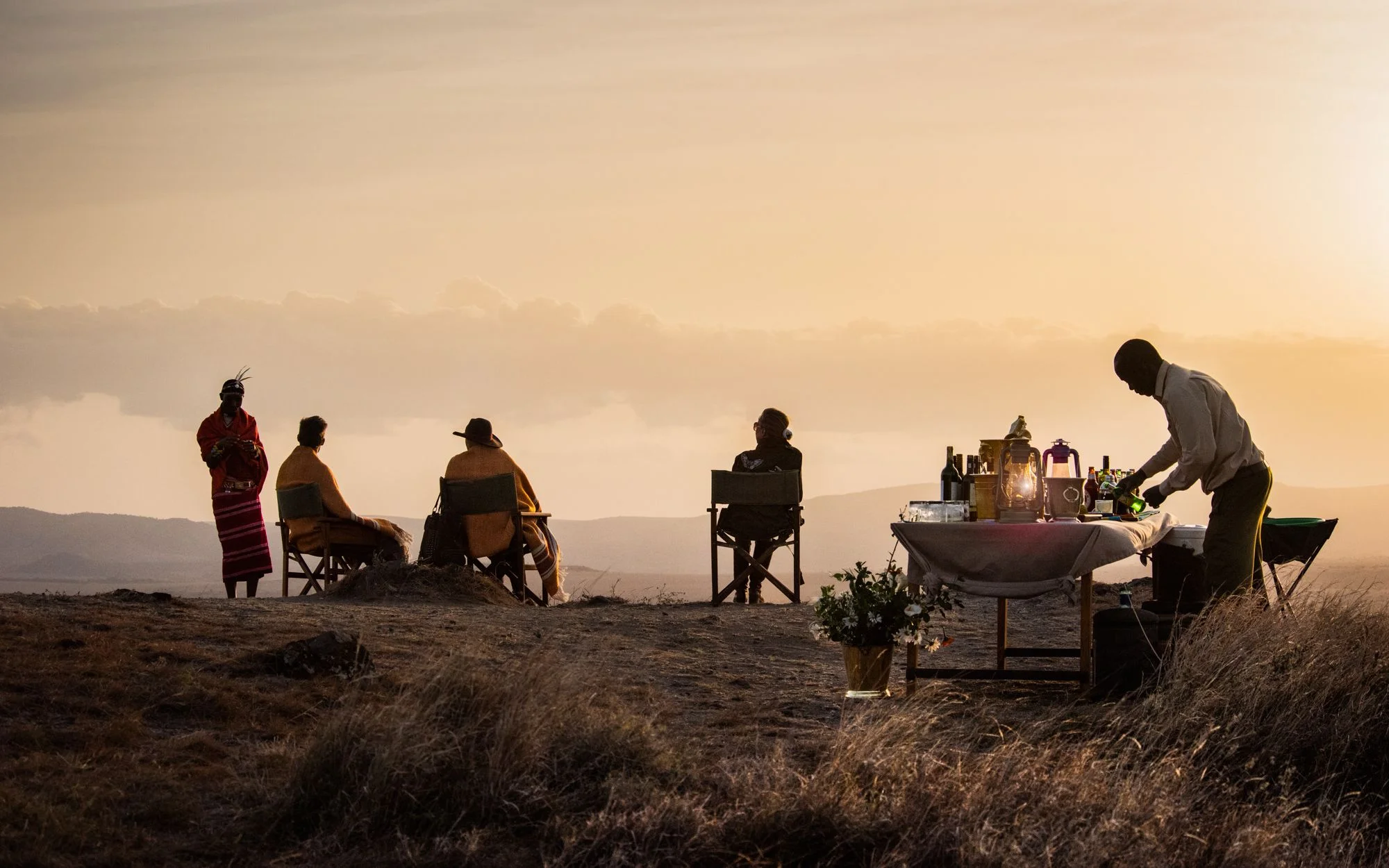 A group of people enjoying a mountain view with a meal.