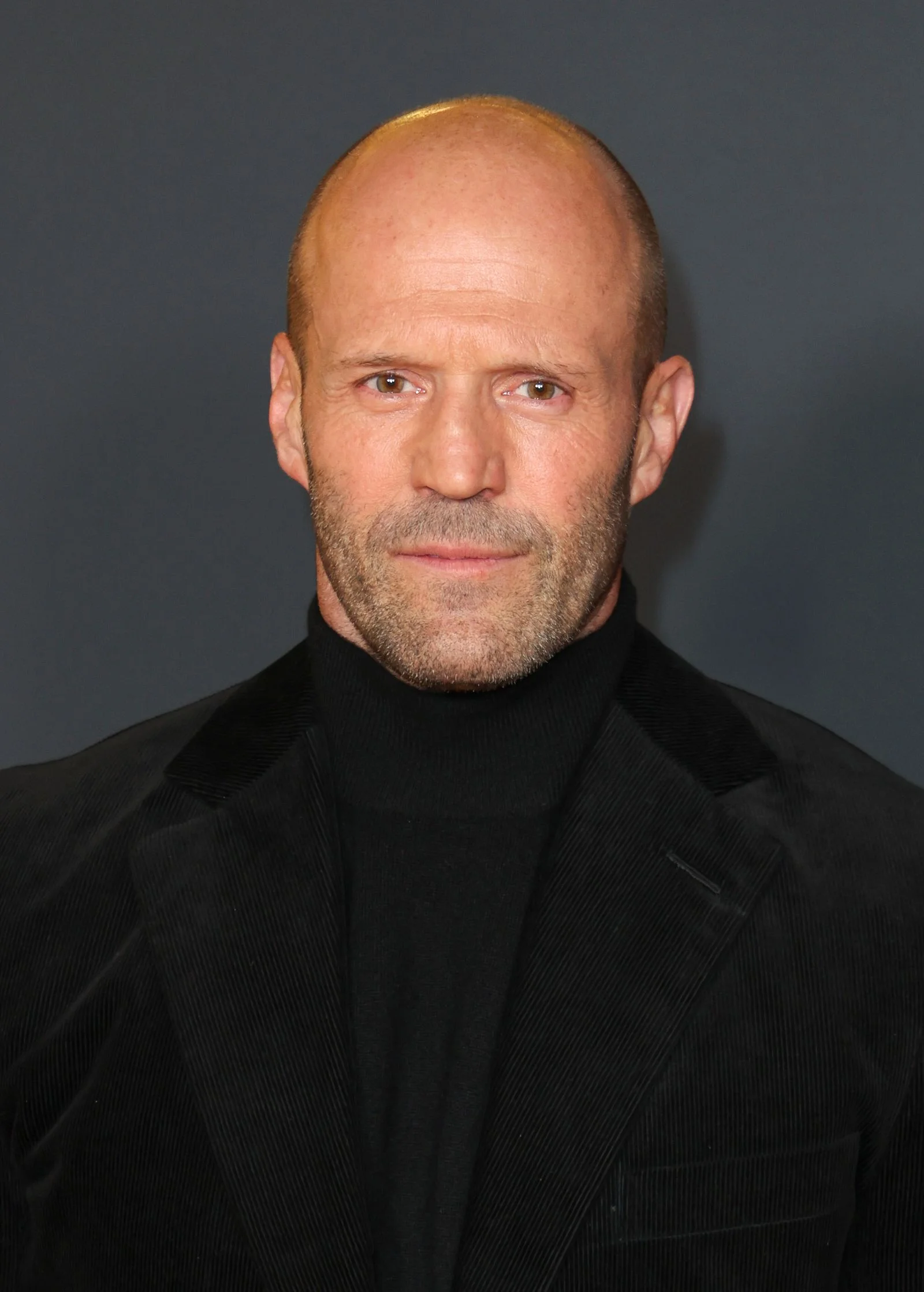 Image may contain Jason Statham Face Head Person Photography Portrait Clothing Coat Adult Jacket Blonde and Hair