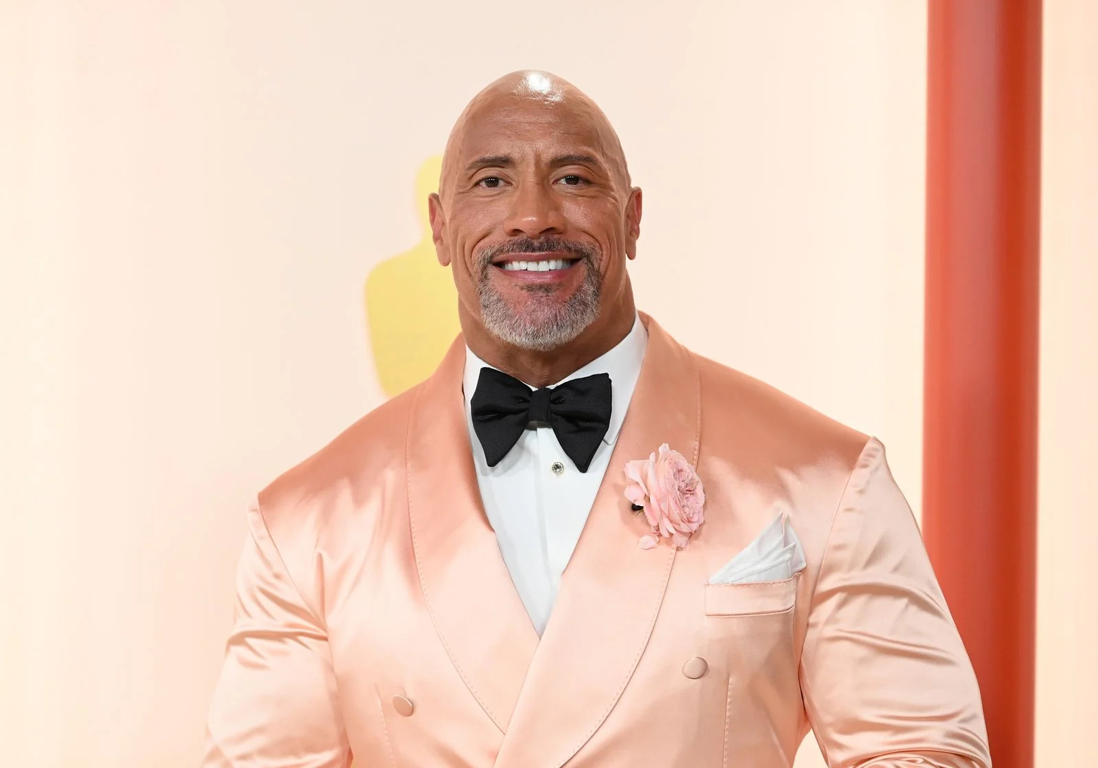 Image may contain Dwayne Johnson Face Happy Head Person Smile Clothing Formal Wear Suit Adult Accessories and Tie