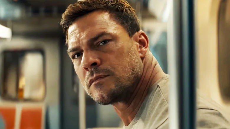 Alan Ritchson's Jack Reacher leans forward on a subway car in Reacher