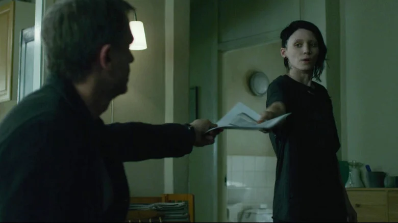 Daniel Craig's Mikael Blomkvist hands papers to Rooney Mara's Lisbeth Salander in The Girl with the Dragon Tattoo