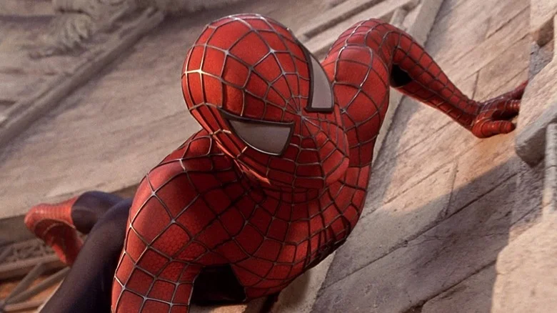 Tobey Maguire as Peter Parker/Spider-Man, wearing his suit and crawling on a wall.