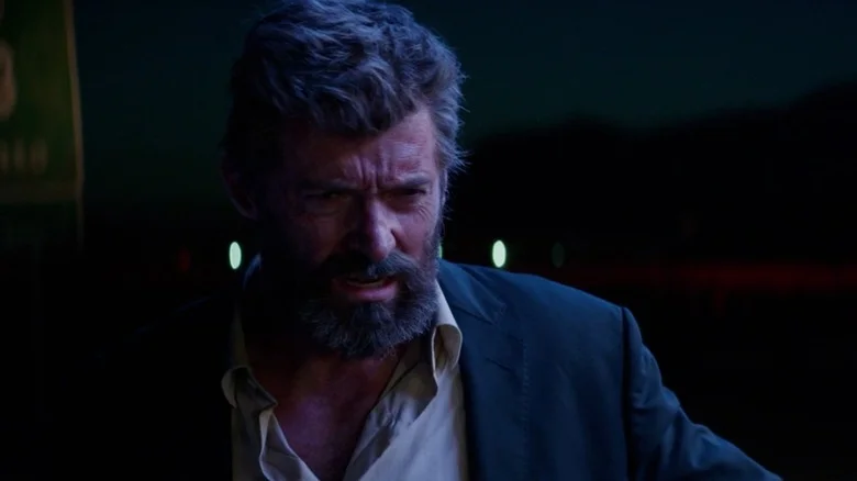 A medium shot of Hugh Jackman as Logan/Wolverine, lit in blue fluorescent light.