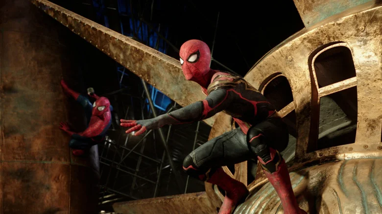 Tom Holland as Peter Parker/Spider-Man and Andrew Garfield as Peter Parker/Spider-Man in Spider-Man: No Way Home, in costume crouched on the top of the Statue of Liberty.