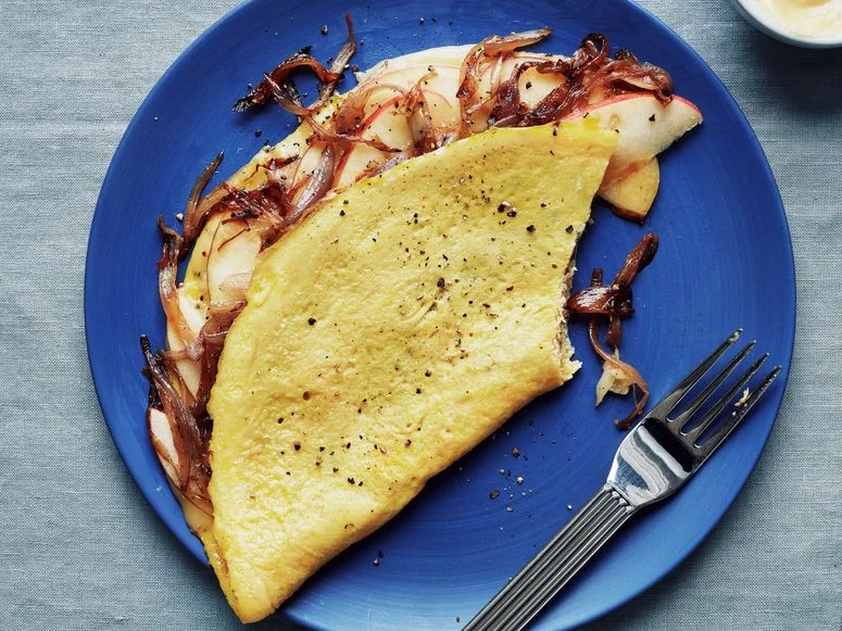 An omelette filled with caramelized onions sliced Fuji apples and fontina cheese and served with Dijon mustard.