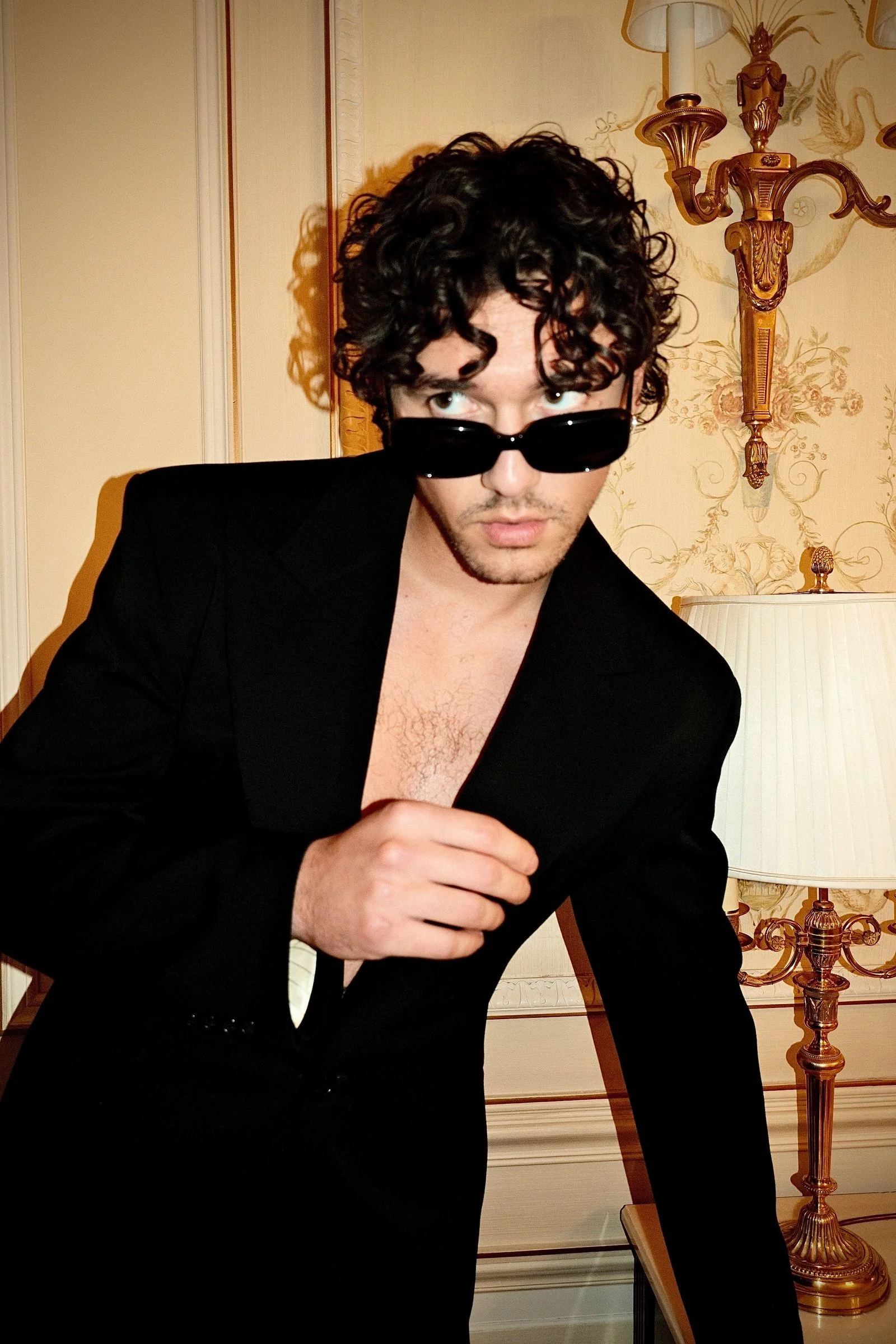 Image may contain Clothing Formal Wear Suit Face Head Person Photography Portrait Accessories and Sunglasses