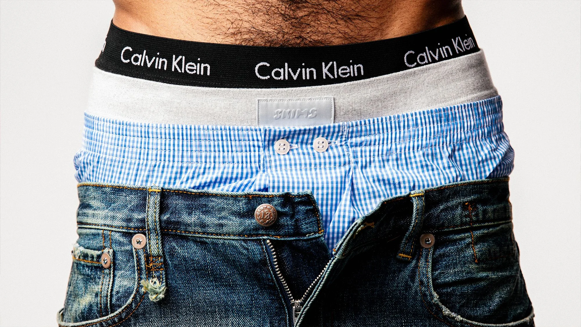 A man wearing three pairs of underwear form Calvin Klein Skims and Derek Rose.