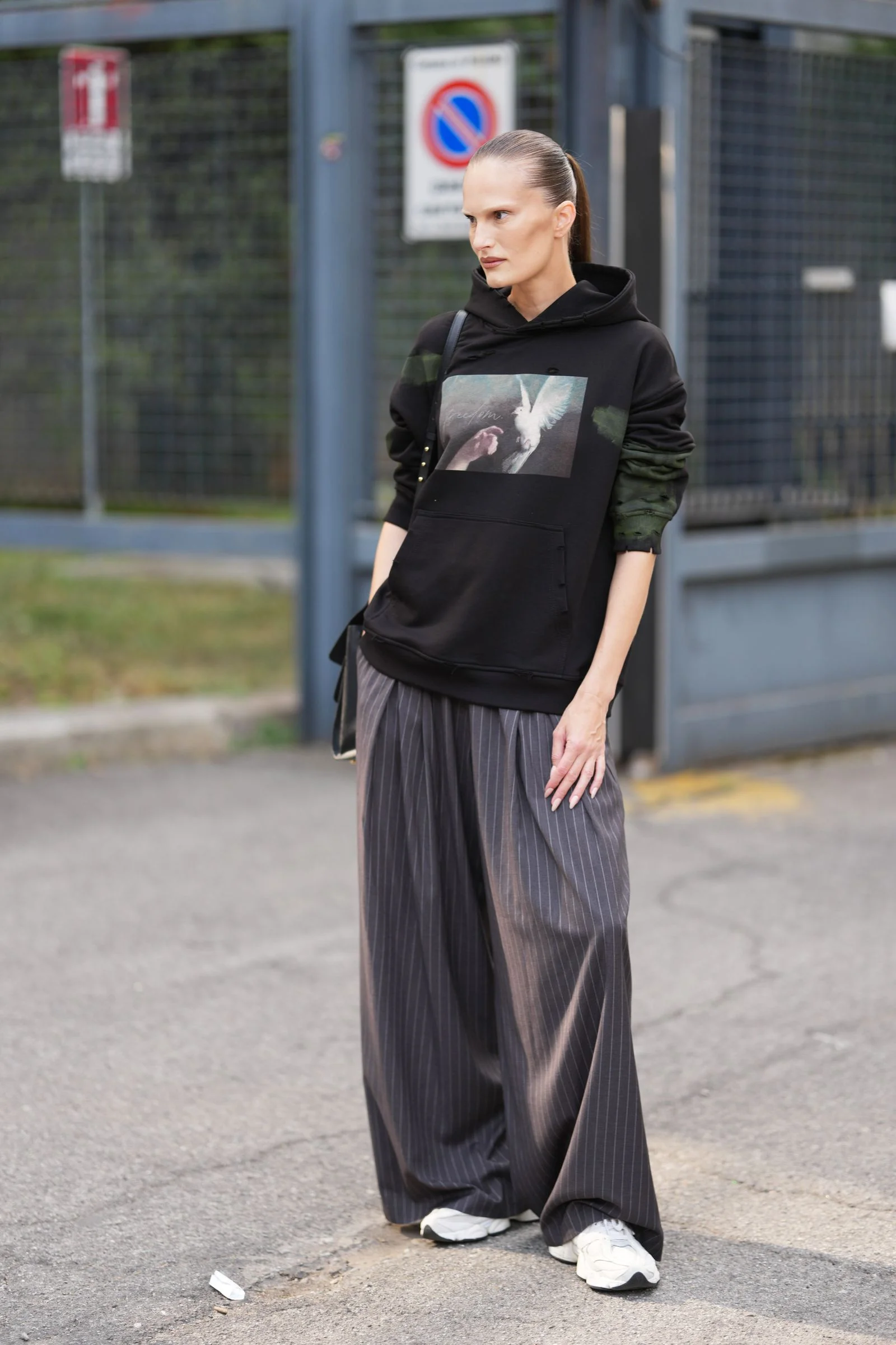 Image may contain Person Adult Clothing Hoodie Knitwear Sweater Sweatshirt Accessories Bag Handbag and Standing