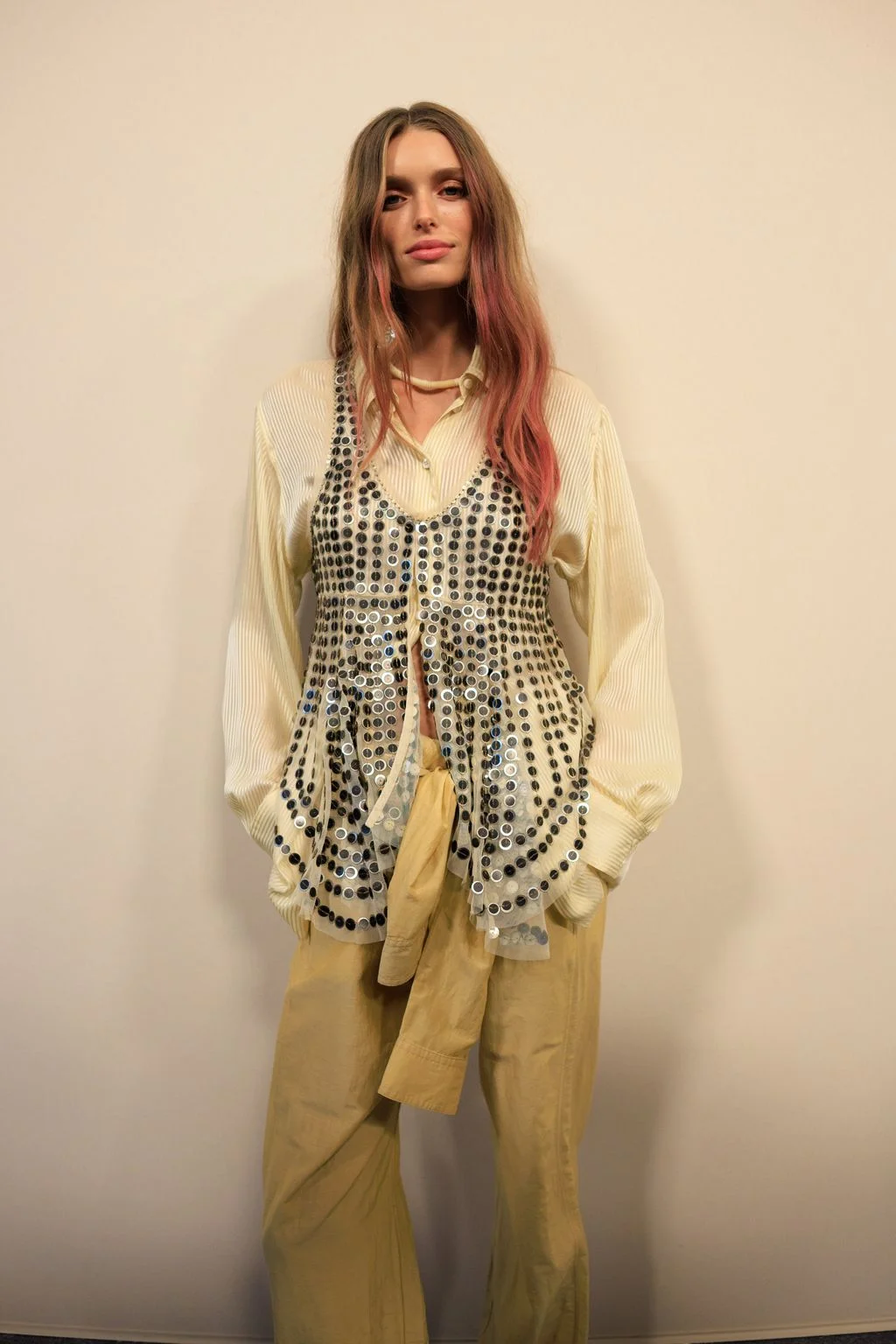 Image may contain Blouse Clothing Accessories Jewelry Necklace Blonde Hair Person Adult Coat and Pants
