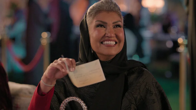 Alanoud holding up a check in Crazy Rich, Incredibly Broke