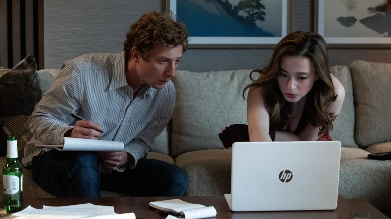 Jeremy Allen White as Jeff Horwitz sitting next to Mikey Madison as Frances Haugen on a couch looking at a laptop in The Social Reckoning
