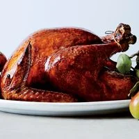 Glazed roast turkey on a platter with apples and pears.