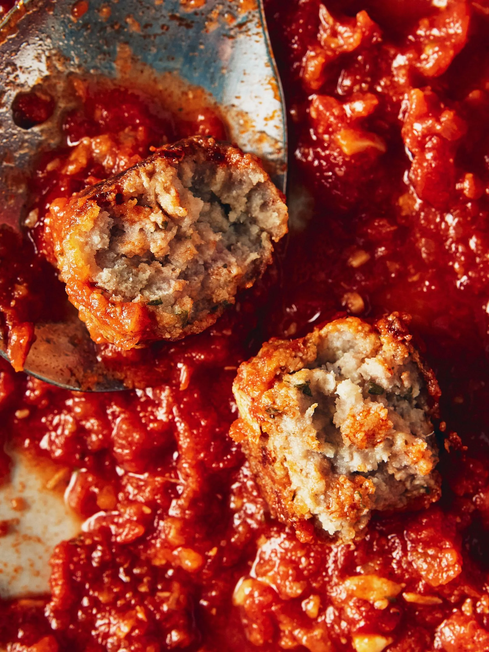 Meatballs made with cottage cheese on marinara sauce broken in half.