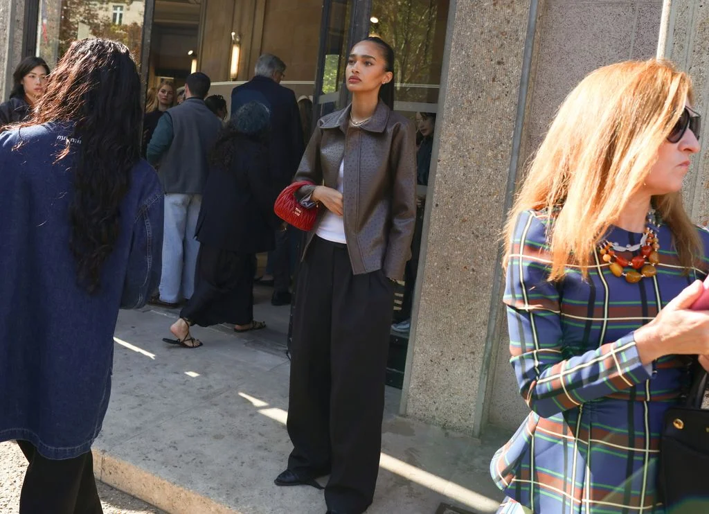 Image may contain Anais Mali Adult Person Clothing Coat Footwear Sandal Accessories Bag Handbag and Standing