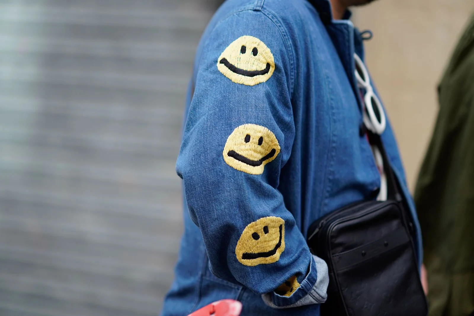Image may contain Clothing Coat Jacket Accessories Bag Handbag Pants Adult Person Walking and Logo