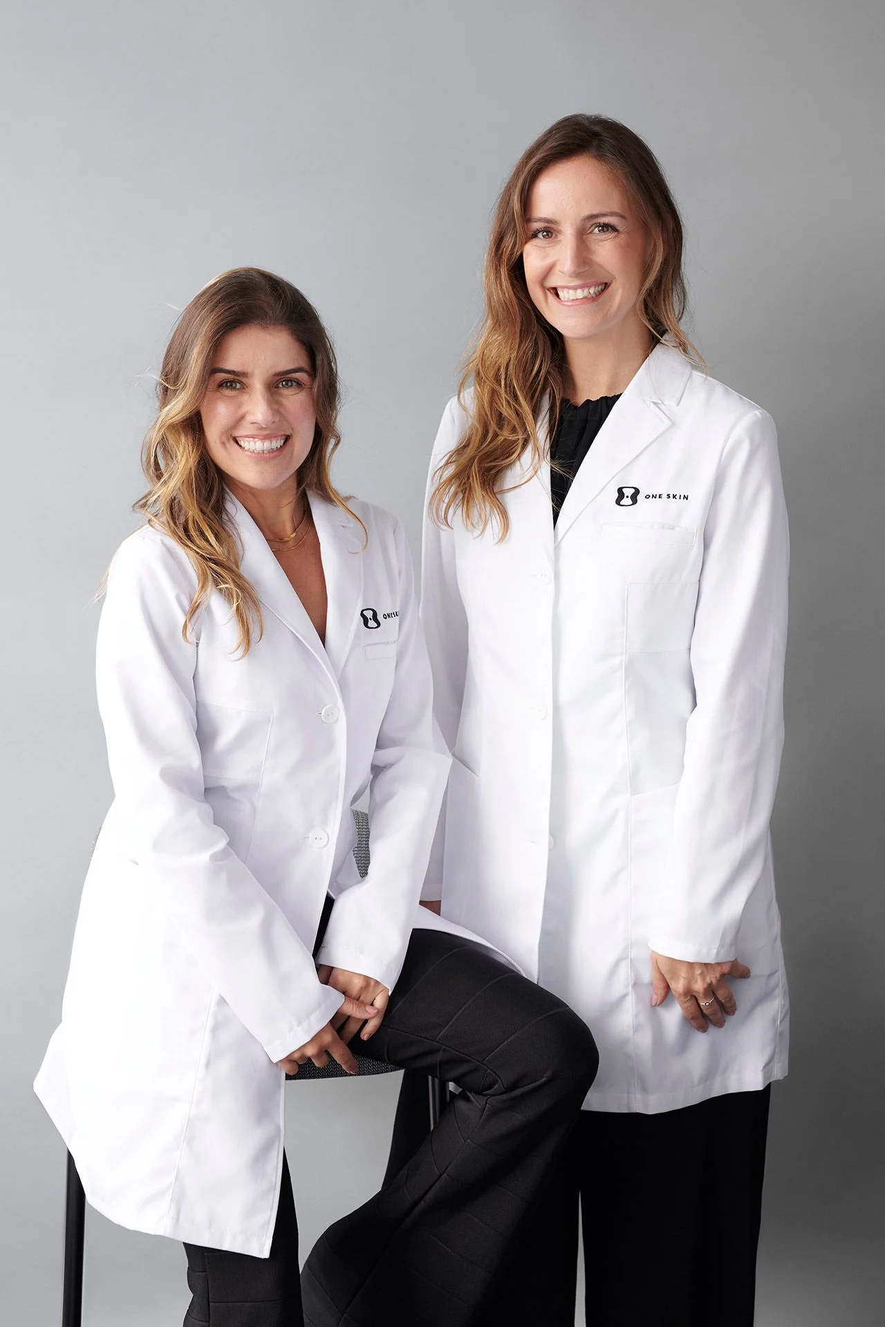 Image may contain Clothing Coat Lab Coat Adult Person Accessories Jewelry Necklace and Ring