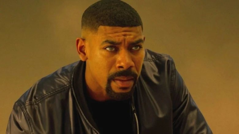 Aaron Pierre as John Stewart wearing a black leather jacket and standing in the middle of a desert in Lanterns